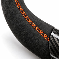 Gros plan sur une couture orange sur le côté en alcantara d'un volant carbone