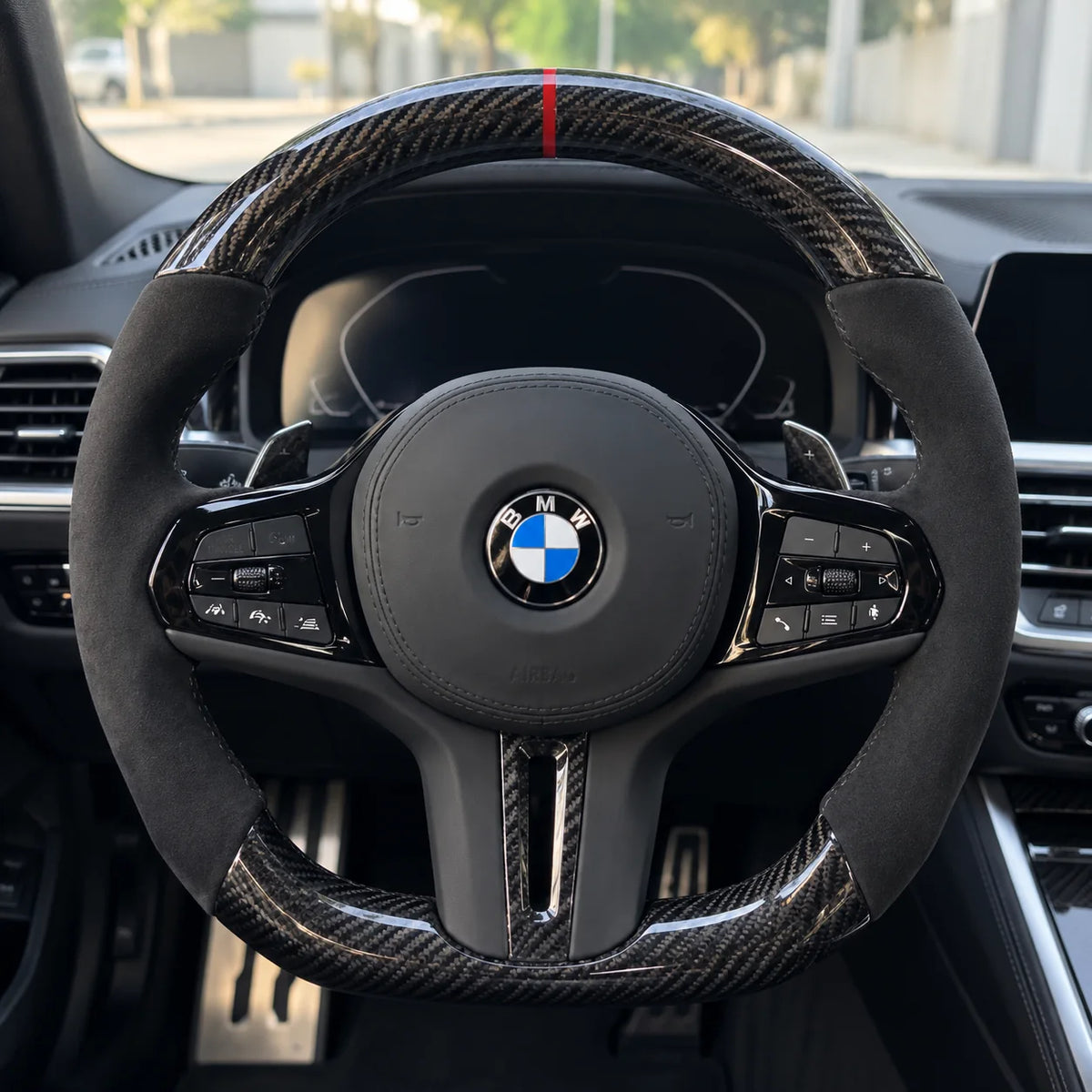 Volant carbone et alcantara monté dans une BMW G20, vu depuis le siège conducteur