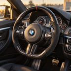 BMW M3 F80 : volant monté vu depuis le siège passager, bas plat et carbone brillant