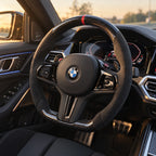 BMW M3 G80 : volant monté vu depuis le siège passager, bas plat et carbone brillant